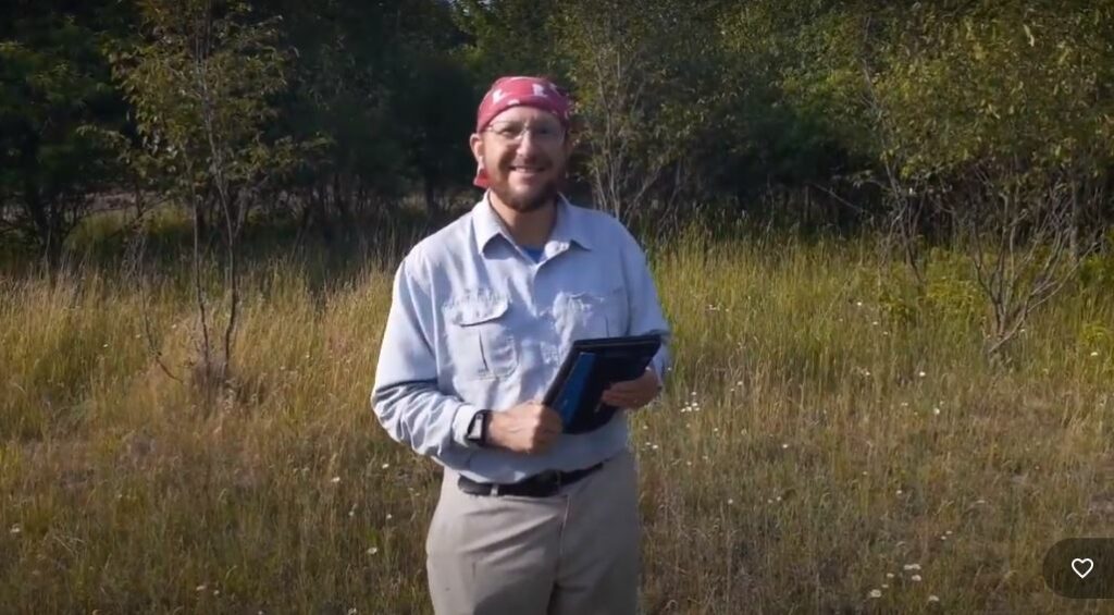 Vince in a field with a solar panel